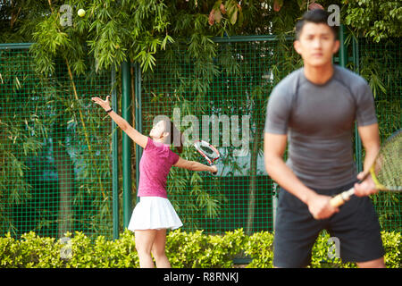 Junge weibliche asiatische tennis player in einem gemischten Doppel dienen Stockfoto