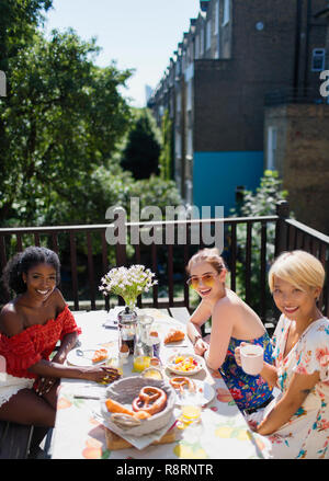 Portrait lächelnden jungen Frauen Freunde genießen Brunch auf der sonnigen Wohnung Balkon Stockfoto