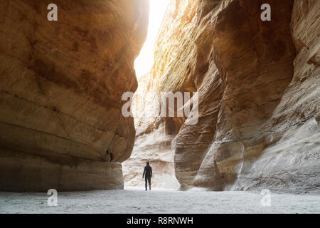 Touristische in schmale Passage der Felsen von Petra Canyon in Jordanien. UNESCO-Weltkulturerbe. Weg durch den Siq Schlucht zu Stein Stadt Petra. einsamer Mann walkin Stockfoto