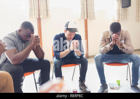 Männer beten mit rosenkränzen im Gebet Gruppe Stockfoto