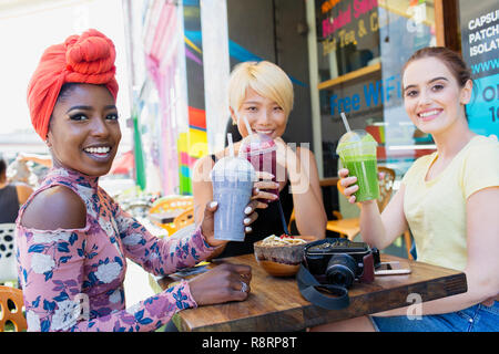 Portrait lächelnden jungen Frauen Freunde trinken Smoothies im Straßencafé Stockfoto