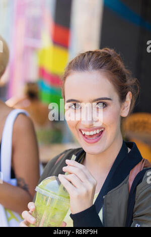 Portrait glückliche junge Frau trinkt grünen Smoothie Stockfoto