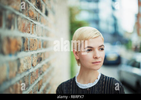 Ruhige junge Frau weg schauen auf städtischen Bürgersteig Stockfoto