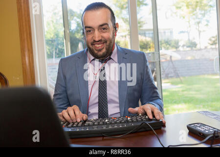 Geschäftsmann mit Sehbehinderung hören auf seinen Computer Stockfoto