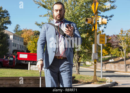 Geschäftsmann mit Sehbehinderung Hören auf sein Telefon und mit Zuckerrohr Stockfoto