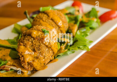 Black-eyed pea Kuchen auf einem Bett von Baby-kopfsalat serviert und mit Remoulade bei Delta Bistro in Tupelo, Mississippi beträufelt. Stockfoto