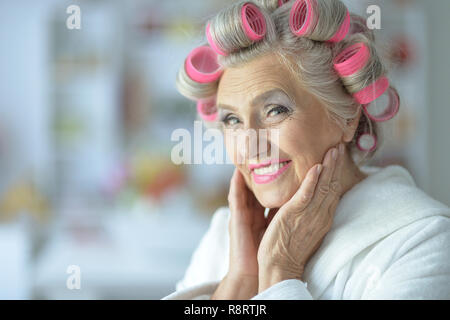 Portrait der älteren Frau im Bademantel und mit Lockenwicklern Stockfoto