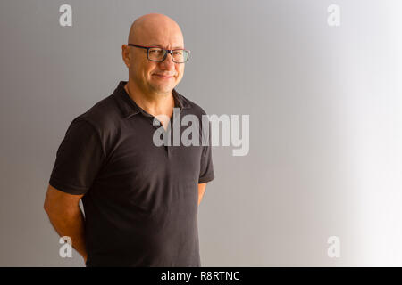 Mitte lässig gekleidet - Büroangestellter stehend mit seine Hände hinter seinem wieder ein Lächeln auf die Kamera über Blau mit Kopie Raum umklammert im Alter von Stockfoto