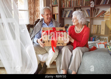 Schönes älteres Paar ihre Weihnachtsgeschenke austauschen zu Hause Stockfoto