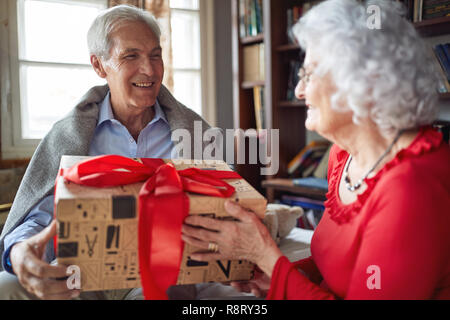 Lächelnd Senior Paar ihre Weihnachtsgeschenke austauschen zu Hause Stockfoto