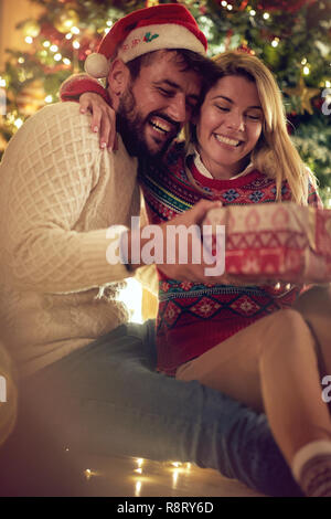 Weihnachten Tradition - Lächelndes Paar mit Geschenk gemeinsam genießen am Heiligabend Stockfoto