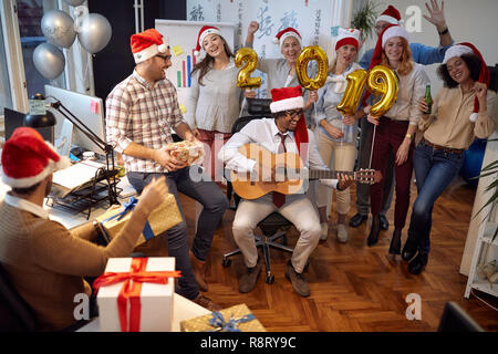 Happy business Arbeiter haben Spaß und Tanz in Santa hat an Weihnachten feiern gemeinsam im Büro Stockfoto