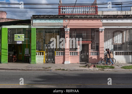 Zwei jungen kubanischen Männer entlang mit dem Fahrrad. Vor bunten Gebäude mit dekorativen Schmiedeeisen schmiedekunst Grills. Ayestarán Straße in Havanna, Kuba. Stockfoto