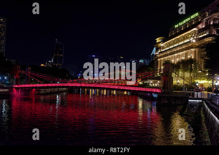 Die cavenaugh Brücke, die einzige Hängebrücke auf dem Singapore River, in rot bei Nacht beleuchtet durch das Fullerton Hotel Stockfoto