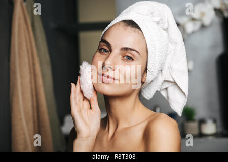 Schöne junge Frau in Badetuch am Bad eingewickelt, mit Powder Puff Stockfoto