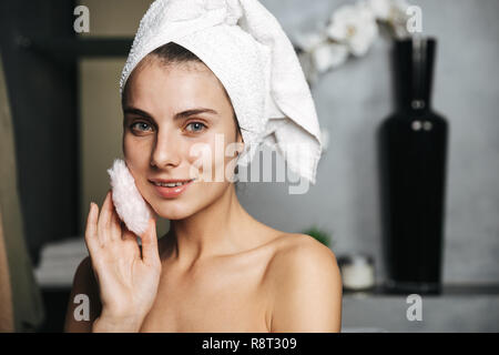 Schöne junge Frau in Badetuch am Bad eingewickelt, mit Powder Puff Stockfoto