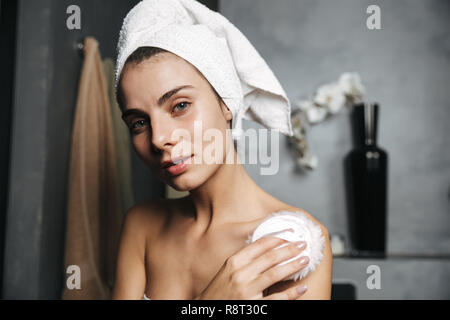 Schöne junge Frau in Badetuch am Bad eingewickelt, mit Powder Puff Stockfoto