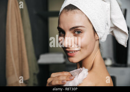 Schöne junge Frau in Badetuch am Bad eingewickelt, mit Powder Puff Stockfoto