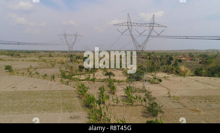 Strommasten Stromversorgung Lager über die ländliche Landschaft. luftaufnahme Strommasten und Hochspannungsleitungen Java, Indonesien. Hohe Spannung Metall post, Turm. Elektrische Stromleitungen über Bäume. Stockfoto