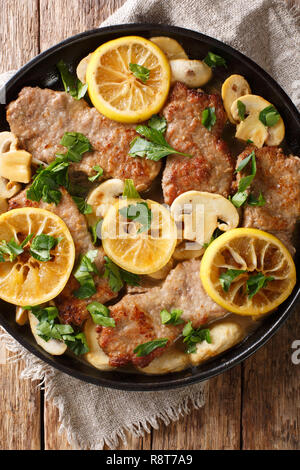 Italienische Kalbfleisch scaloppini mit Pilzen und Zitronen in einer Soße close-up in einer Pfanne auf dem Tisch. Vertikal oben Ansicht von oben Stockfoto