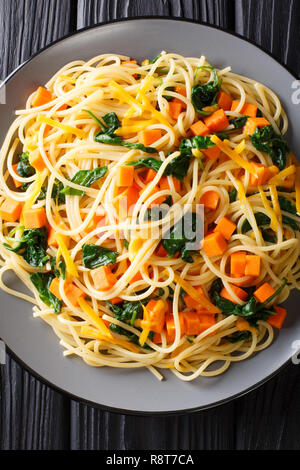 Kalorienarme Mittagessen von Spaghetti mit Kürbis, Spinat und Cheddar Käse close-up auf einem Teller auf den Tisch. Vertikal oben Ansicht von oben Stockfoto