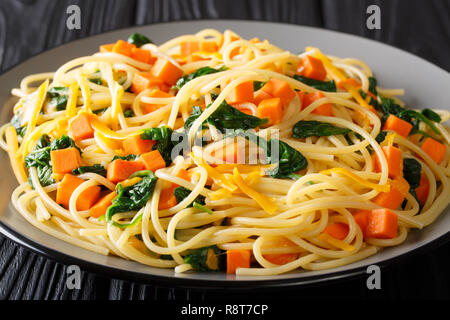 Gesund im Herbst essen Spaghetti mit Kürbis, Spinat und Cheddar Käse close-up auf einem Teller auf den Tisch. Horizontale Stockfoto