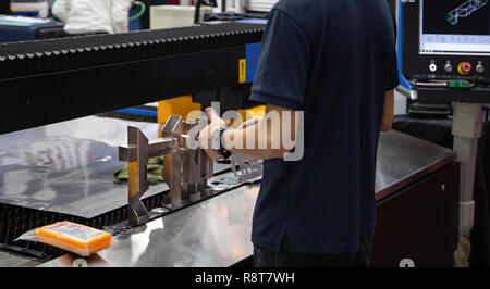 Arbeiter bedienen CNC-Laserschneidanlage schneiden Rohr Stockfoto