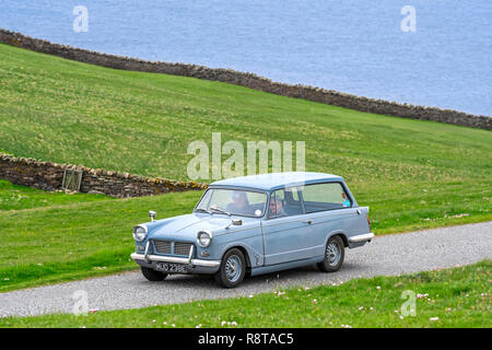 Ältere Paare fahren 1967 classic car Triumph Herald 1200 Immobilien entlang der Küstenstraße Stockfoto