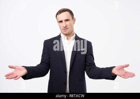 Was es über. Jungen zornigen Mann auf grauem Hintergrund ist an einem Verlust, isoliert, hilflose Geste mit Arm und Hände Stockfoto
