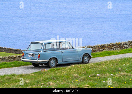 Ältere Paare fahren 1967 classic car Triumph Herald 1200 Immobilien entlang der Küstenstraße Stockfoto