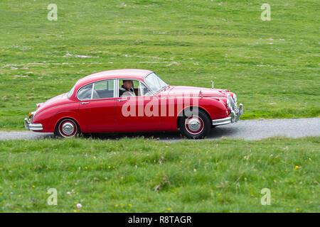 Rot 1962 Jaguar Mk 2/Jaguar Mk II 3,8 Liter klassische Sportwagen fahren entlang der Landstraße durch Wiese Stockfoto