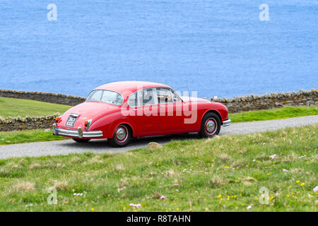 Rot 1962 Jaguar Mk 2/Jaguar Mk II 3,8 Liter klassische Sportwagen entlang der Küstenstraße fahren Stockfoto