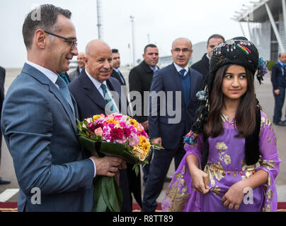Erbil, Irak. 18 Dez, 2018. Heiko Maas (SPD), Außenminister, ist auf dem Flughafen von Bagdad (Irak) von einer jungen Frau mit einem Blumenstrauß begrüßt. Nach Kuwait Maas Besuche im Irak. Credit: Jens Büttner/dpa-Zentralbild/dpa/Alamy leben Nachrichten Stockfoto