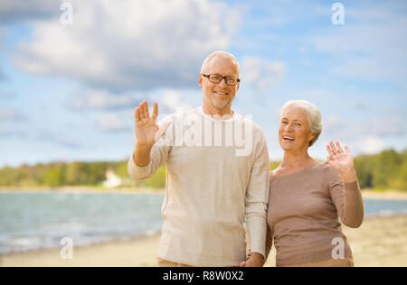Gerne älteres Paar winkende Hände am Strand Stockfoto