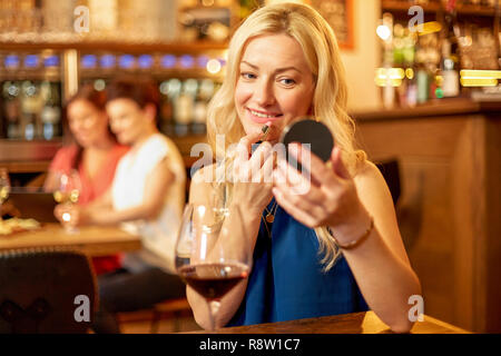 Frau mit Lippenstift Anwendung der Verfassung an Wein bar Stockfoto