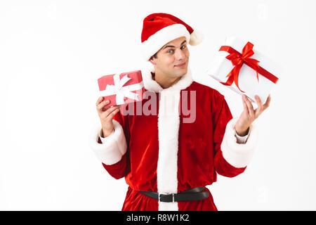 Portrait von freundlichen Mann 30 s in santa claus Kostüm und Red Hat holding Geschenkboxen auf weißem Hintergrund im Studio isoliert Stockfoto