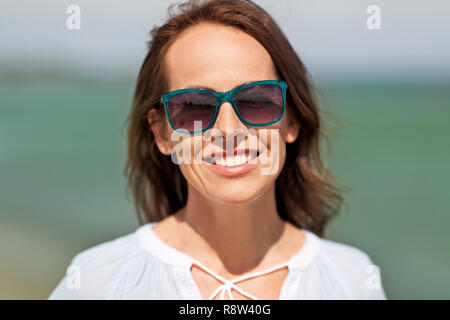 Glücklich lächelnde Frau mit Sonnenbrille auf Sommer Strand Stockfoto