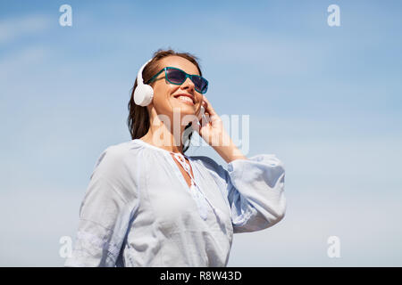 Frau mit Kopfhörer über blauen Himmel Stockfoto