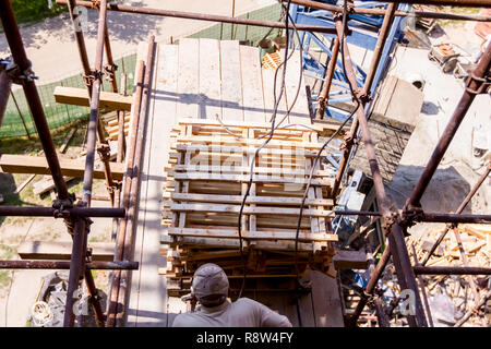 Anwender, Arbeiter ist die Anordnung der Paletten im Stapel für den Kran auf der Baustelle zu ergreifen. Stockfoto