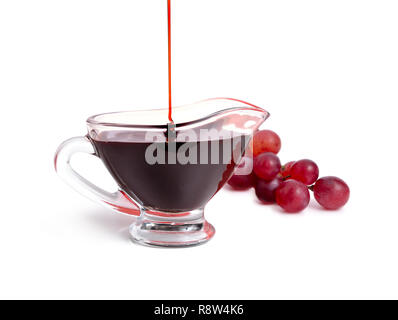 Balsamico Essig in der Schüssel mit Trauben. Auf weissem Hintergrund. Stockfoto