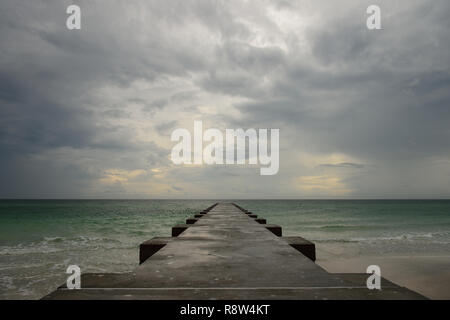 Sandstrand mit konkreten Pier bis in das Meer mit einem bewölkten stürmischen Himmel an der Golfküste in Florida, USA Stockfoto