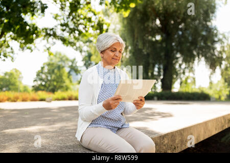 Ältere Frau liest Zeitung am Sommer, Park Stockfoto