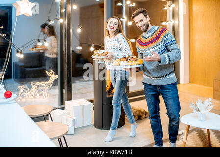 Junges Paar vorbereiten für den festlichen Abendessen in das moderne Haus während der Winterferien Stockfoto