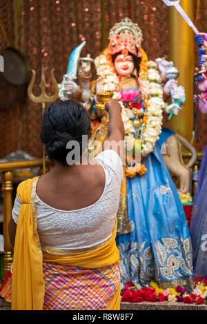 Die ARTI RITUAL. Ein frommer Hindu Frau betet und Wellen Feuer vor der Statuen von Gottheiten an einem Tempel in Queens, New York City. Stockfoto