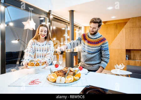 Junges Paar in festlichen Abendessen sitzen zusammen in das moderne Haus während der Winterferien Stockfoto