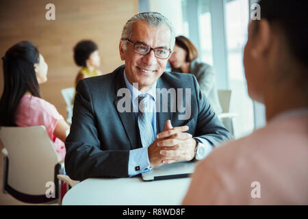 Lächelnd Geschäftsmann hören von Kollegen in der Cafeteria Stockfoto
