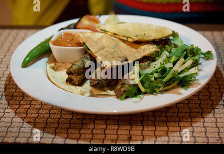 Kibbeh orientalisches Restaurant mit Rind, Lamm, Ziege oder das Kamel Fleisch serviert mit gebratenen grünen Salat, Pita, iolated. Reisen in den Nahen Osten land Königreich Jordanien Stockfoto