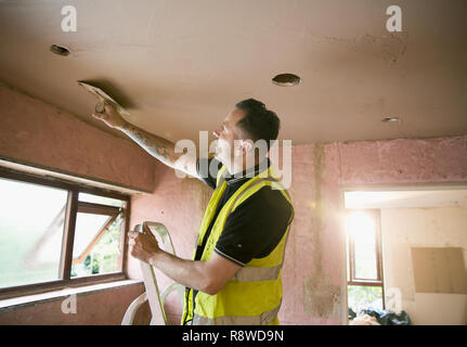 Bauarbeiter verputzen Decke im Haus Stockfoto