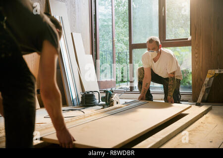 Bauarbeiter anheben Holz im Haus Stockfoto