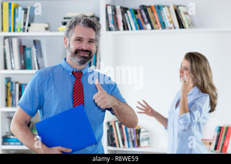 Im mittleren Alter Geschäftsmann mit Daumen nach oben im Büro Stockfoto